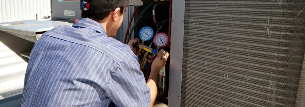 HVAC technician servicing a condenser unit in Harrison